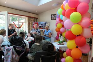 Group of people in a lounge next to a large display of colourful balloons