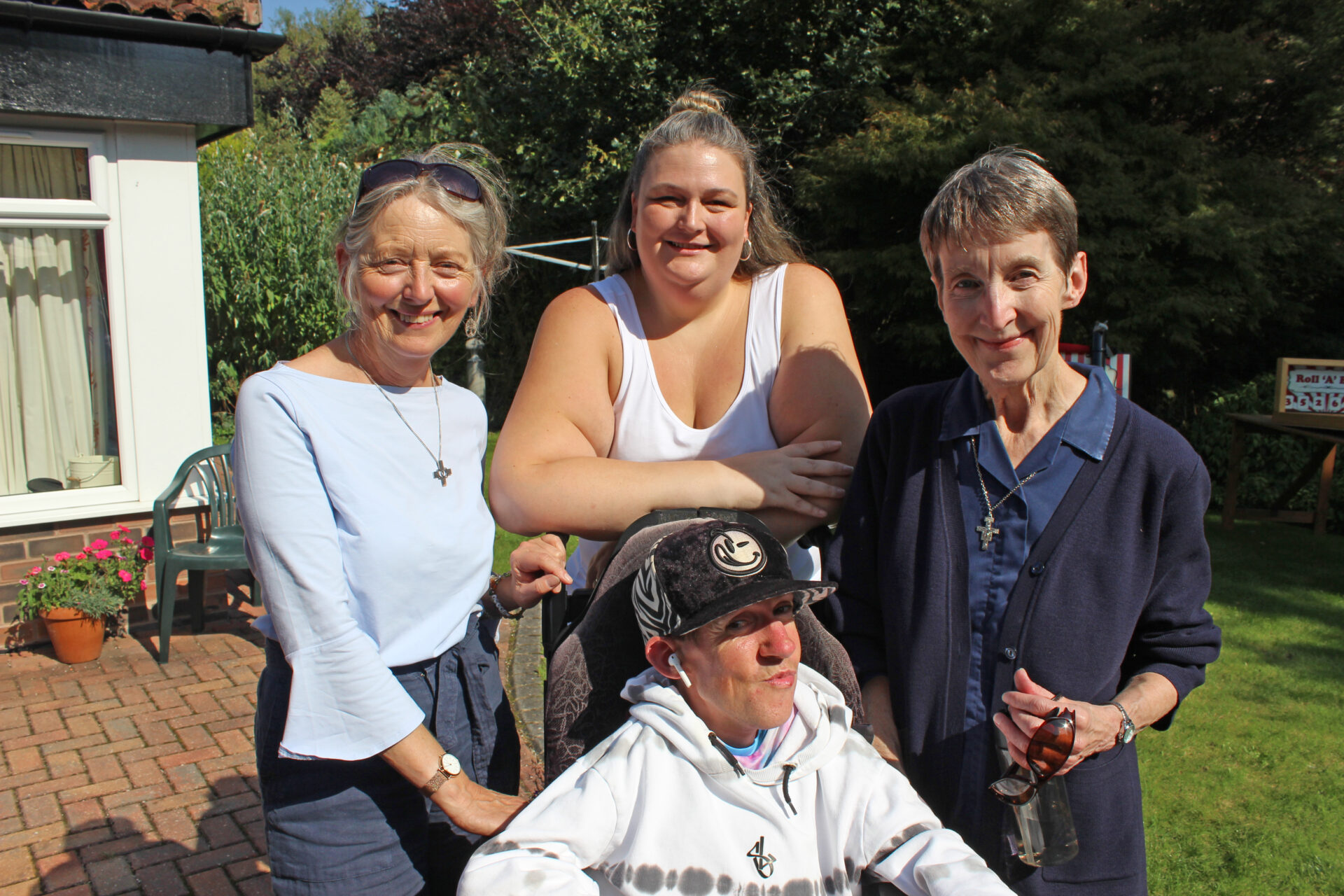 Three women stood behind a young man in a wheelchair smiling