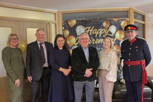 Group of people stood in front of a happy retirement banner