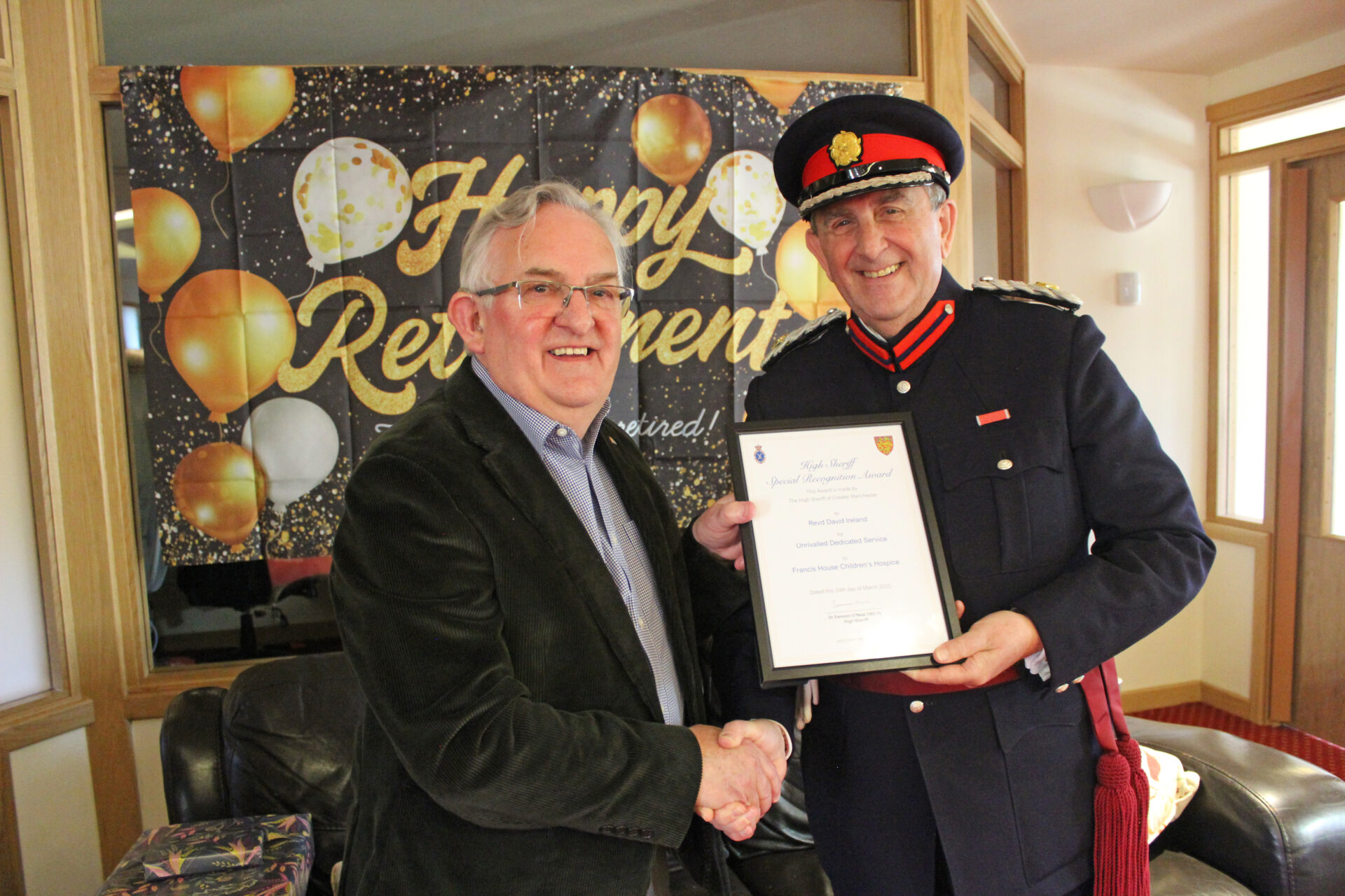 A man dressed in a uniform presents an award certificate to another man