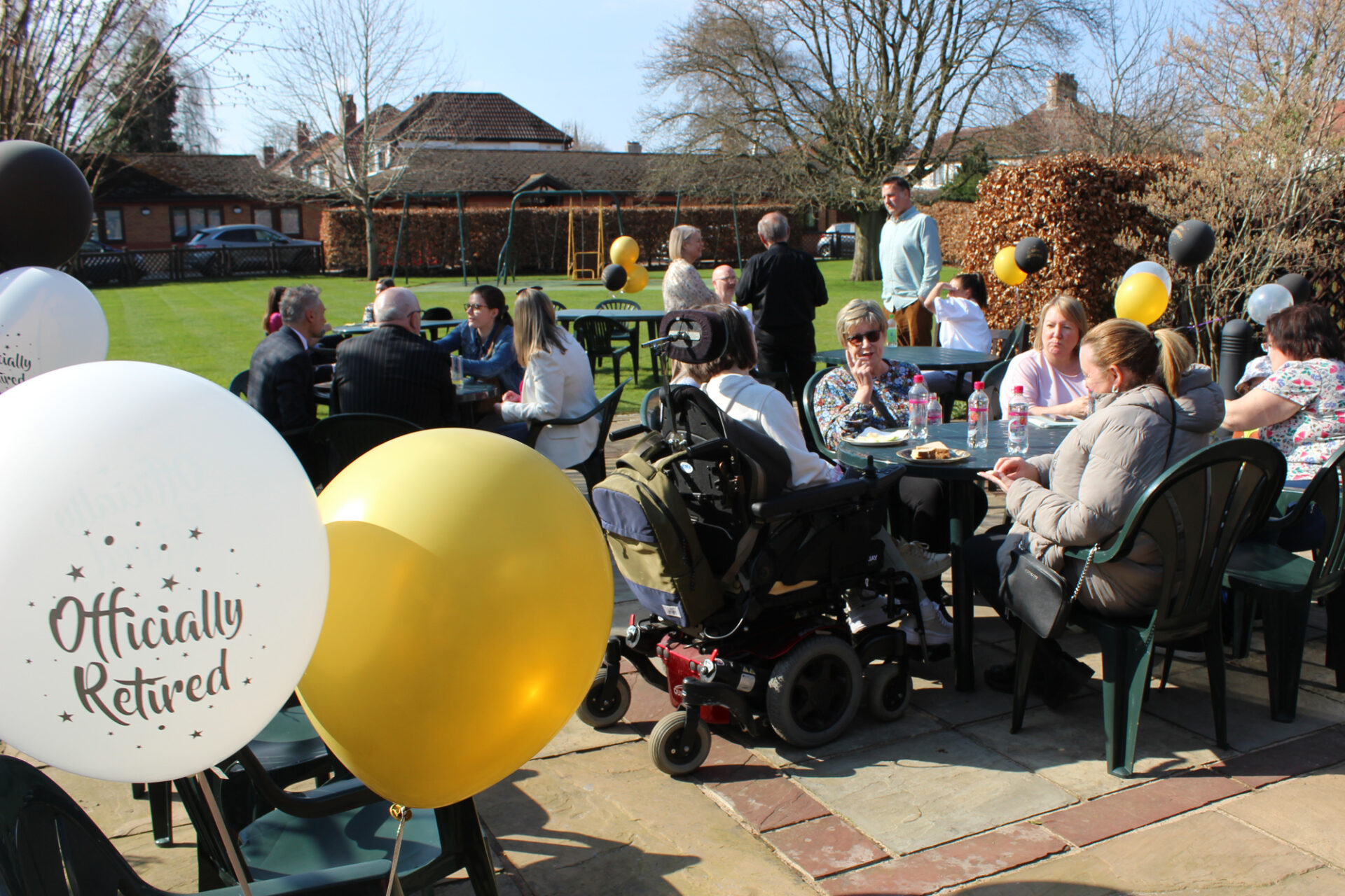 People sat in a garden at a party with balloons