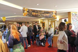 People at a party stood underneath a large banner saying Happy retirement