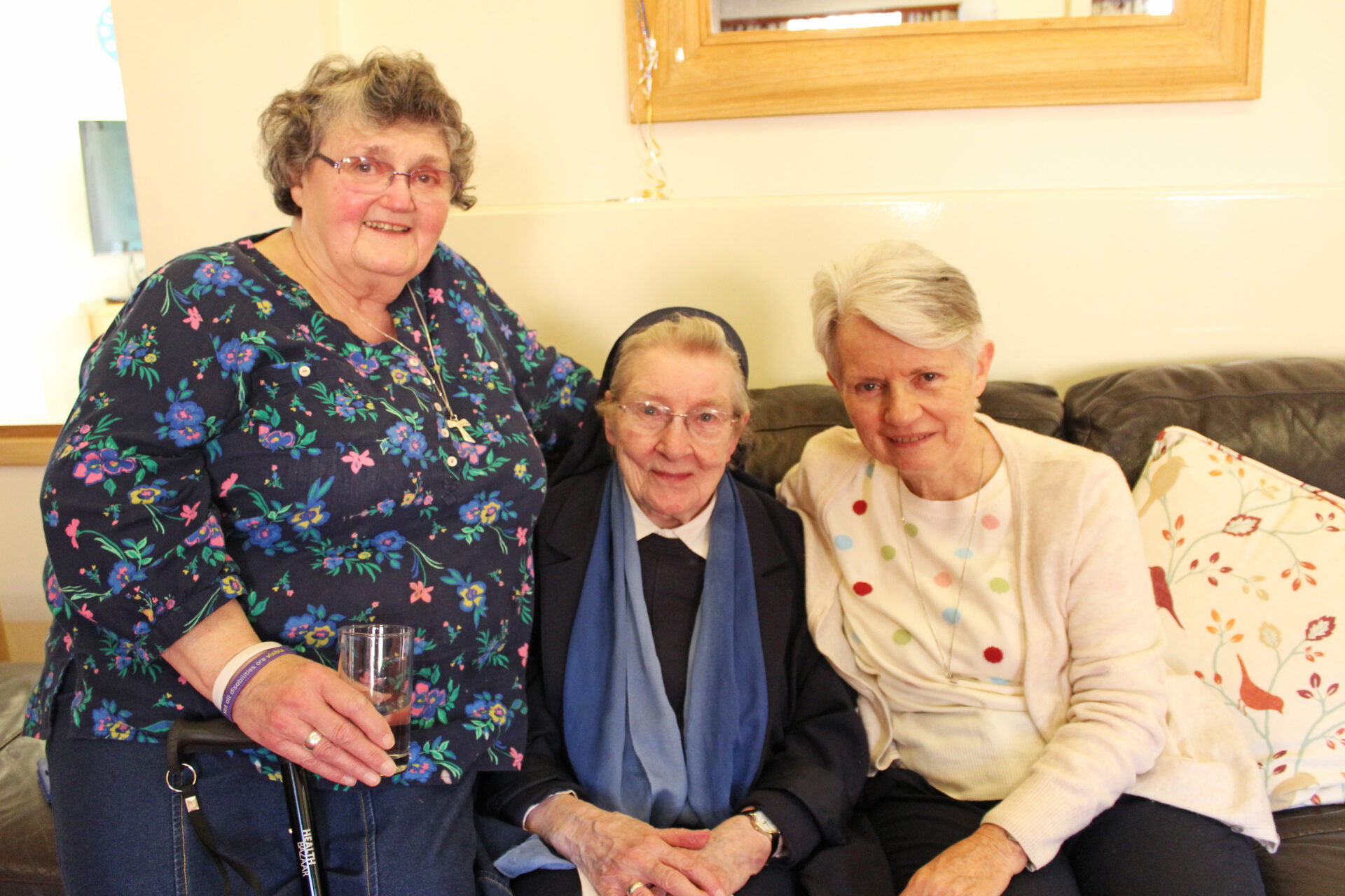 Three women sat on a sofa smiling at the camera