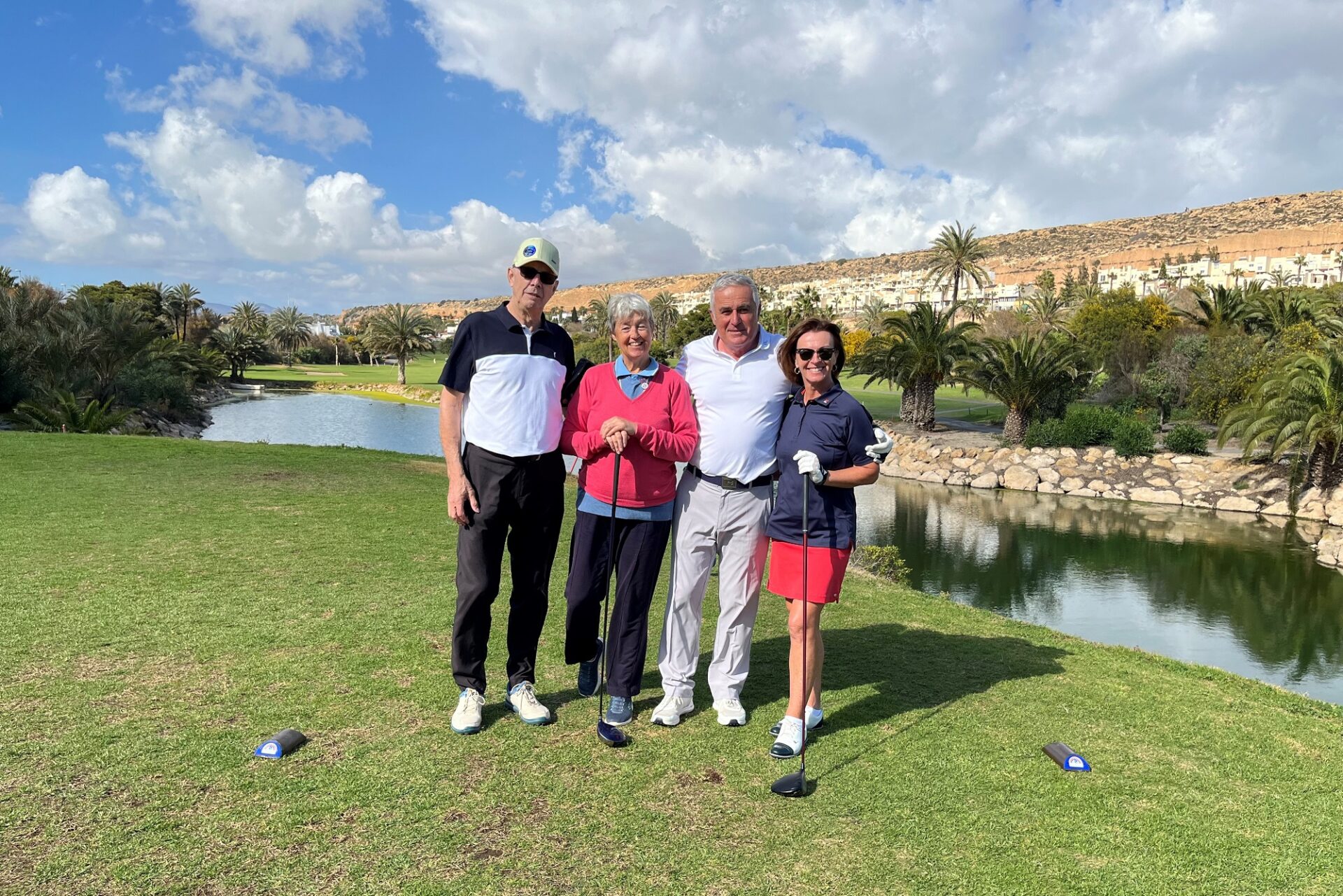 Small group of people stood on a golf course holding golf clubs