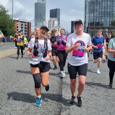 Group of runners smiling at the camera running the city streets of Manchester