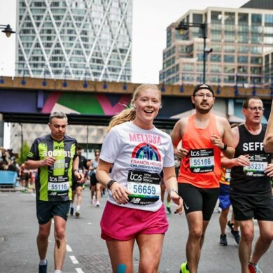 Men and women wearing running vests and shorts running the streets of London in the London marathon