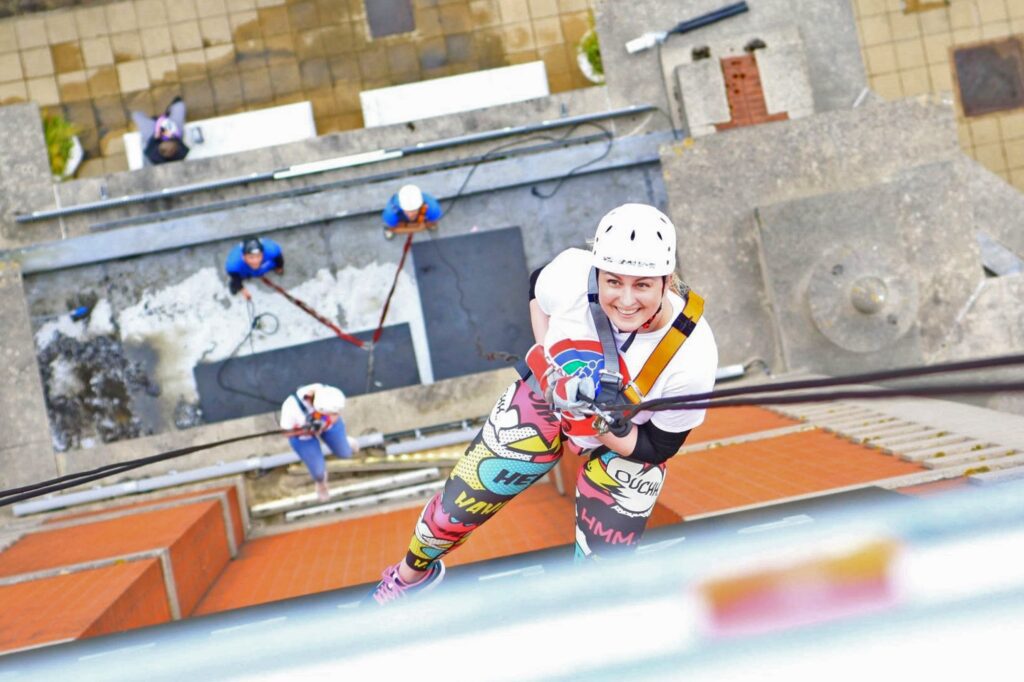 Woman abseiling down a tower smiling at the camera