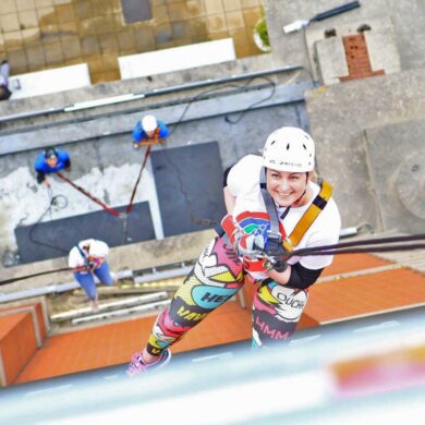 Woman abseiling down a tower smiling at the camera