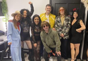 People dressed as various singers stood backstage in a dressing room
