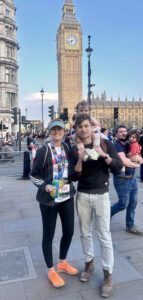 Woman holding a London Marathon medal stood with a man with a child on his shoulders stood with Big Ben in the background