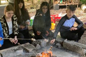 Young people toasting marsh mallows around a fire pit