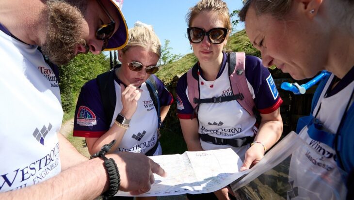 Four people wearing rucksacks looking at a map