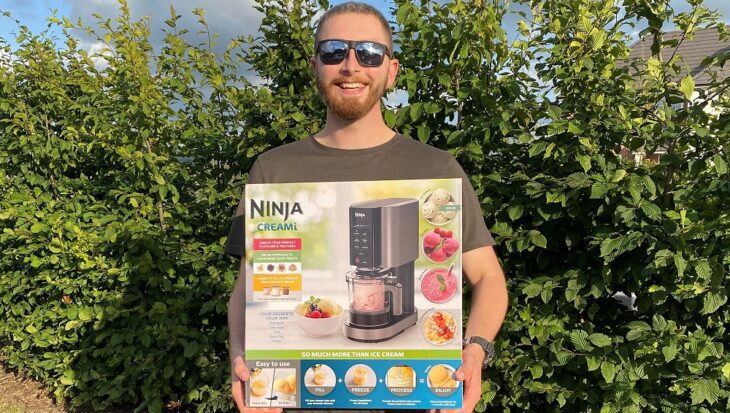 Man wearing sunglasses smiling at the camera holding a boxed ice cream maker