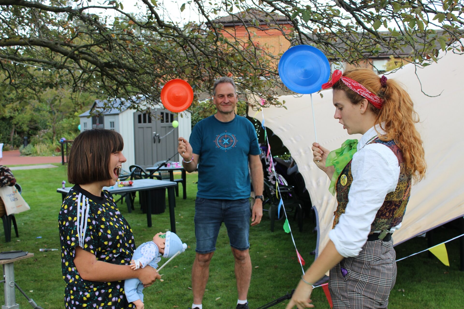 People spinning coloured plates on sticks at a festival event