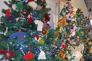 Assorted decorations and knitted items on rows of Christmas trees
