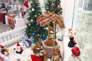 Shop window display of Christmas themed wishing well, soft toys and snow balls.