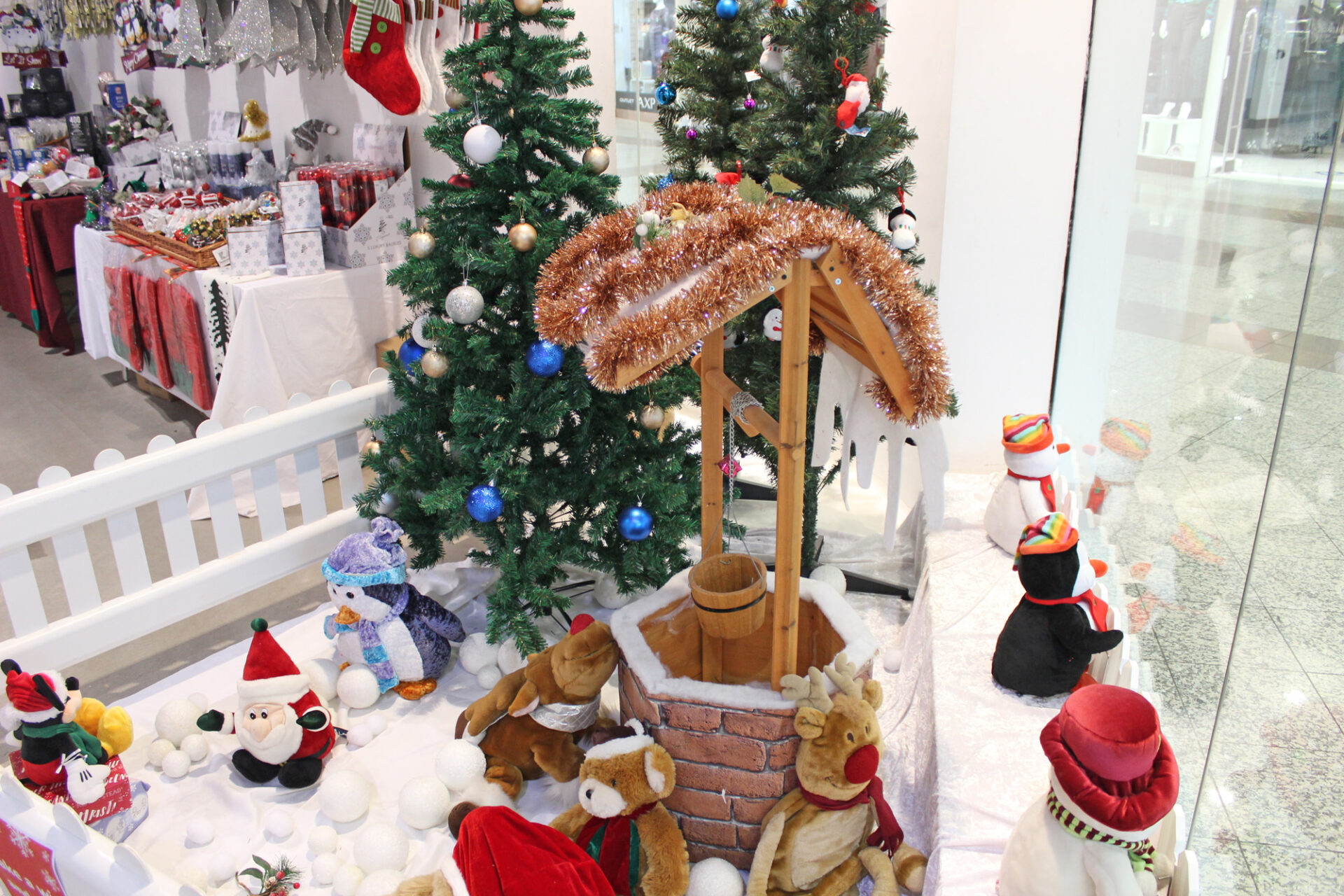 Shop window display of Christmas themed wishing well, soft toys and snow balls.