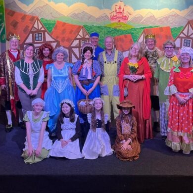 Group of people dressed in pantomime costumes stood on a theatre stage