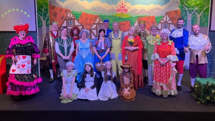 Group of people dressed in pantomime costumes stood on a theatre stage