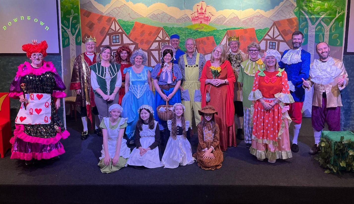 Group of people dressed in pantomime costumes stood on a theatre stage