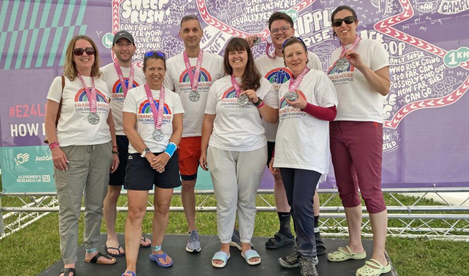 Group of people stood holding medals after completing a charity challenge