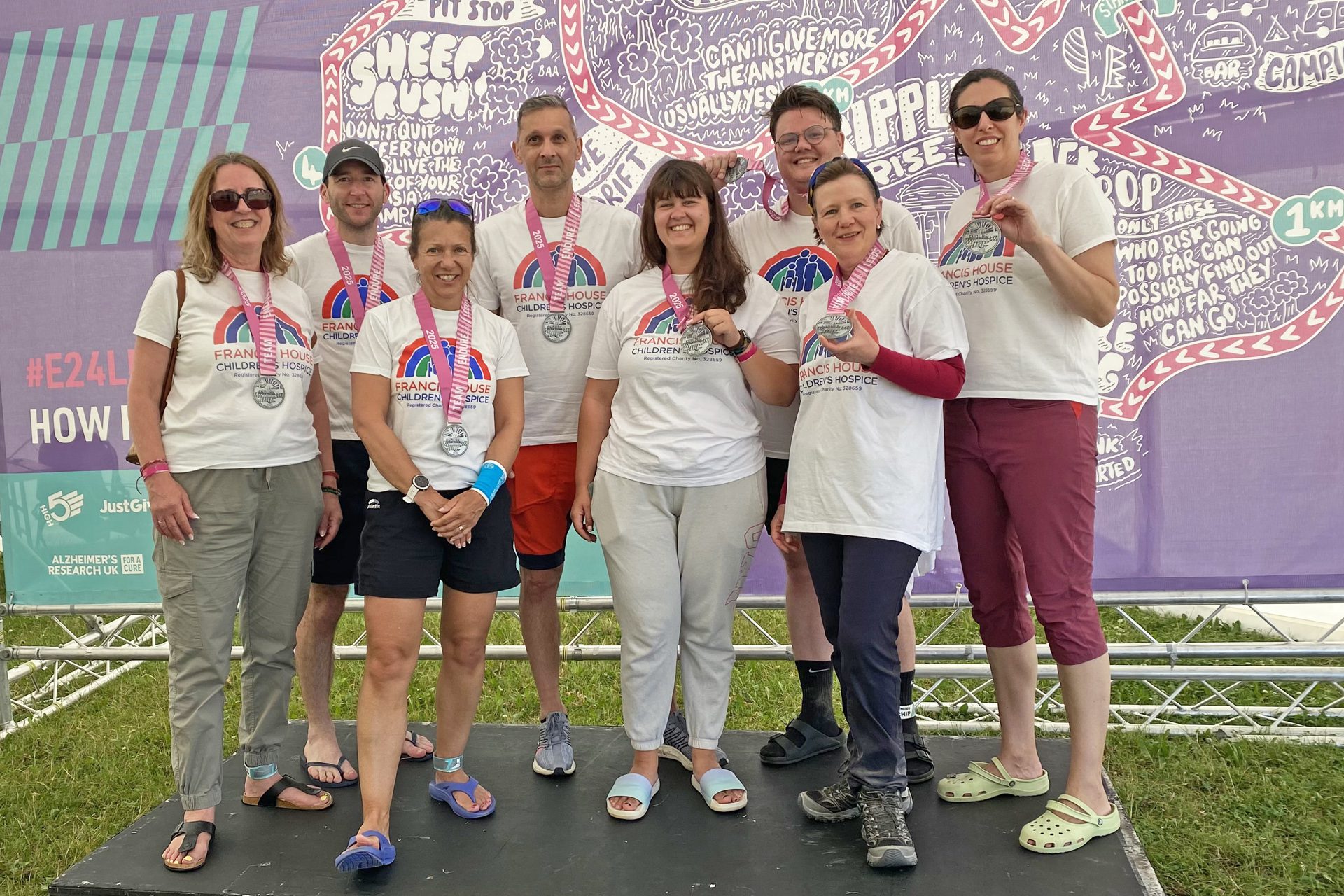 Group of people stood holding medals after completing a charity challenge