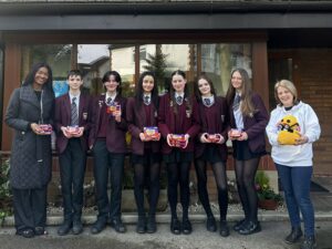 Students in school uniform stand in line outside Francis House holding creme egg boxes