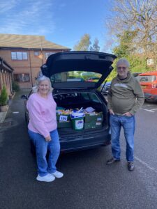 A woman and a man stand beside an open car boot loaded with crates of Easter Chicks and fundraising buckets