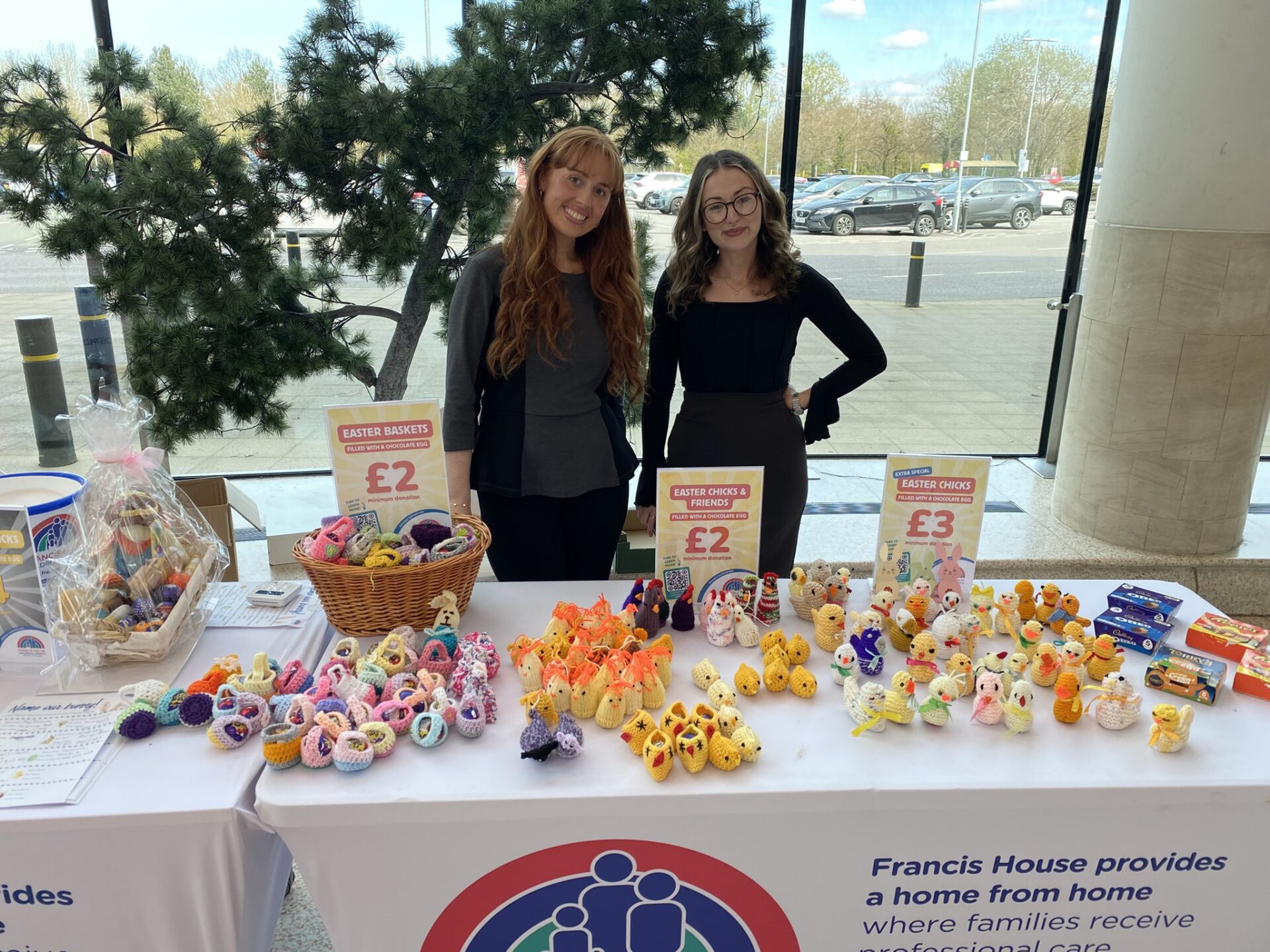 Two women stand behind a stall selling chicks in a shopping centre