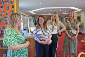 A group of women stood in a colourful lounge on a tour of Francis House children's hospice