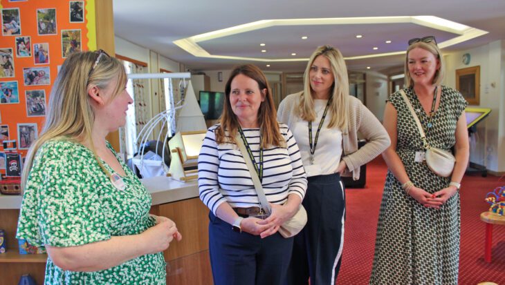 A group of women stood in a colourful lounge on a tour of Francis House children's hospice