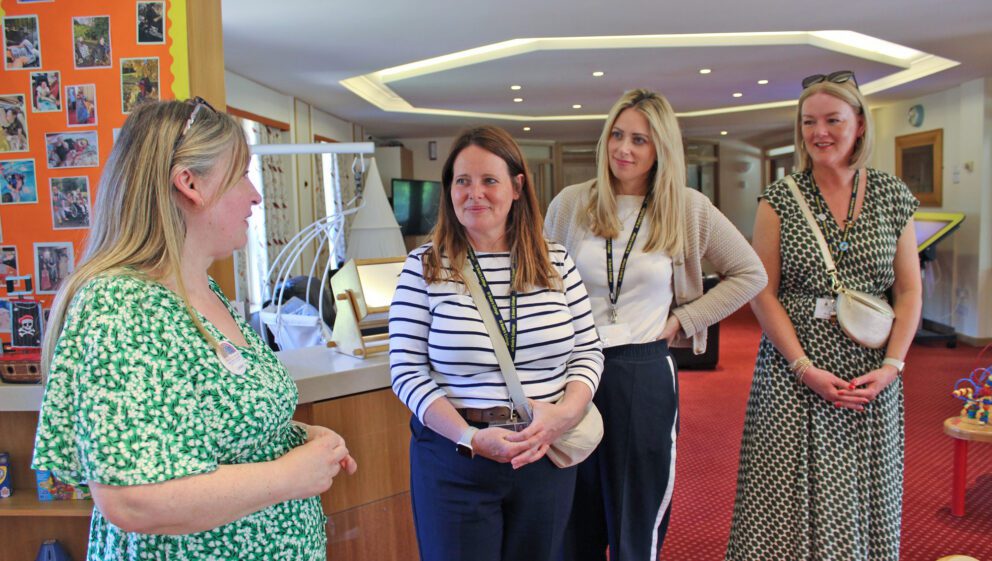 A group of women stood in a colourful lounge on a tour of Francis House children's hospice