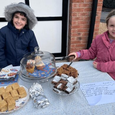 Two children selling cakes outside their house