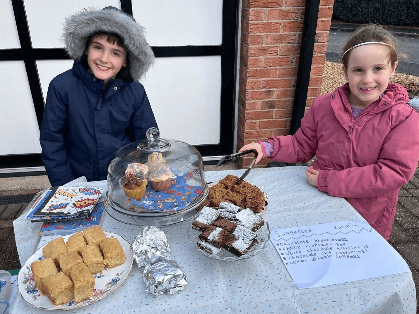 Two children selling cakes outside their house
