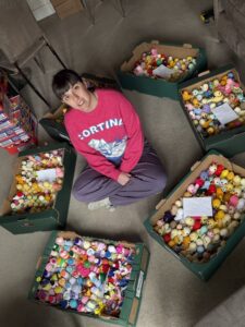 A young woman sits cross legged in her living room, surrounded by boxes full of Easter chicks