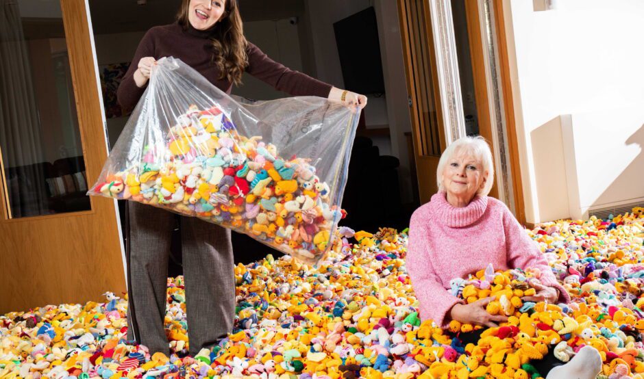 Rachel Nasiri tips a large bag of knitted chicks on the floor next to Maria Dunbobbin sat surrounded by knitted chicks and bunnies