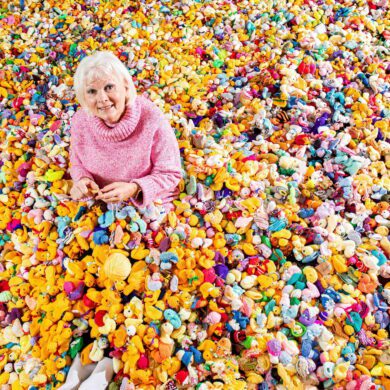 Woman Maria Dunbobbin sat in a pile of thousands of colourful knitted chicks