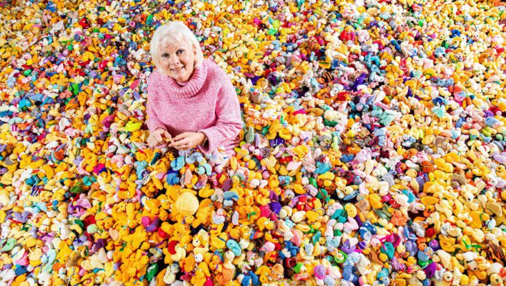 Woman Maria Dunbobbin sat in a pile of thousands of colourful knitted chicks