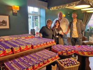 A group of people standing behind a large table covered with boxes of Cadbury's creme eggs