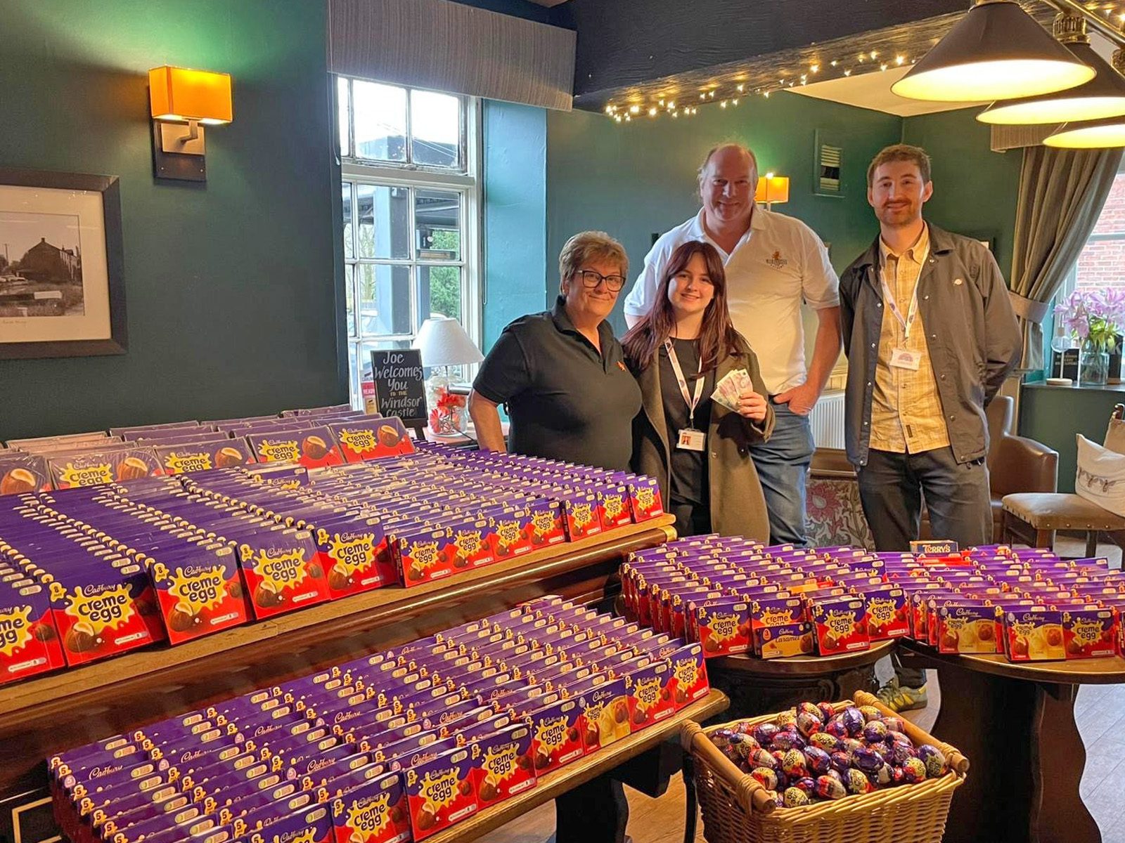 A group of people standing behind a large table covered with boxes of Cadbury's creme eggs