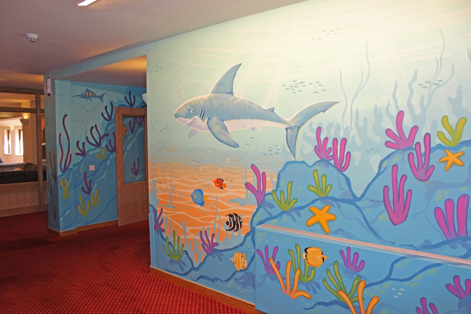 Mural of an undersea world with a smiling shark and colourful sea weed and fish