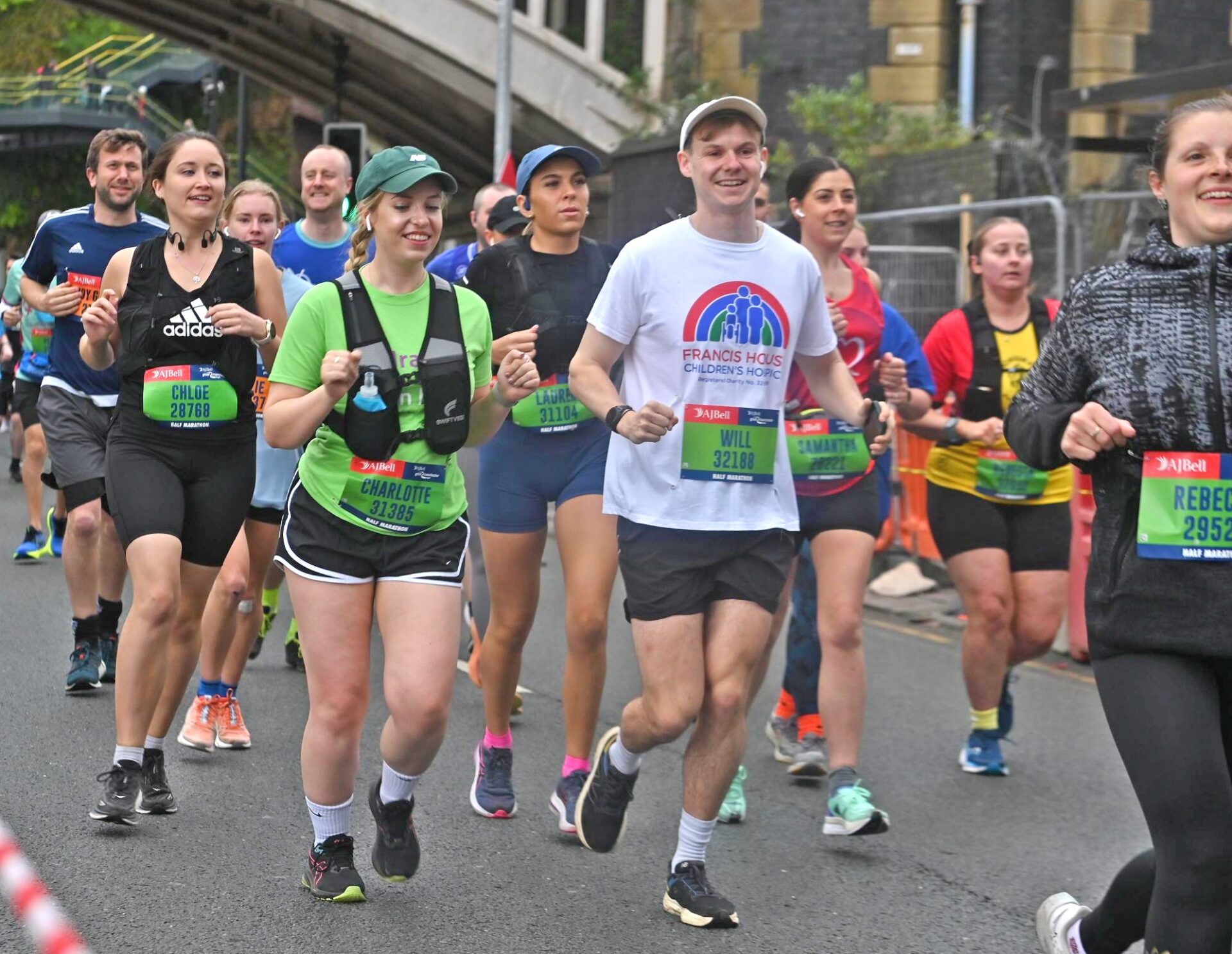 Group of people wearing running shorts and t-shirts running on a road in Manchester