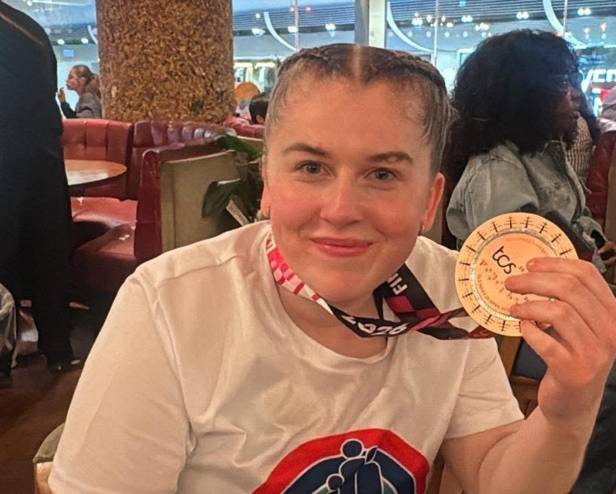 Young woman with plaited hair hols a London Marathon medal.
