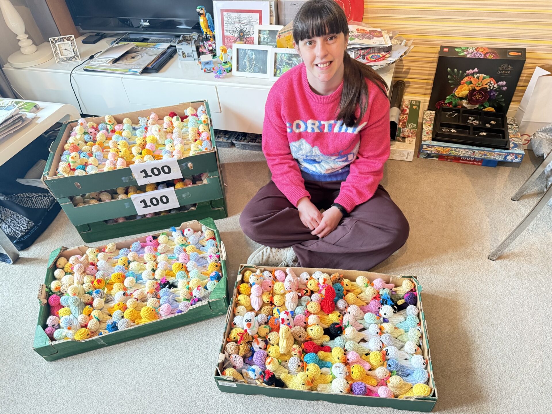 Woman sat on the floor with boxes full of colourful knitted chicks