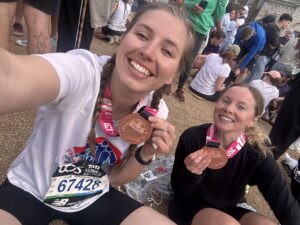 Two women holding London Marathon medals taking a selfie photo.