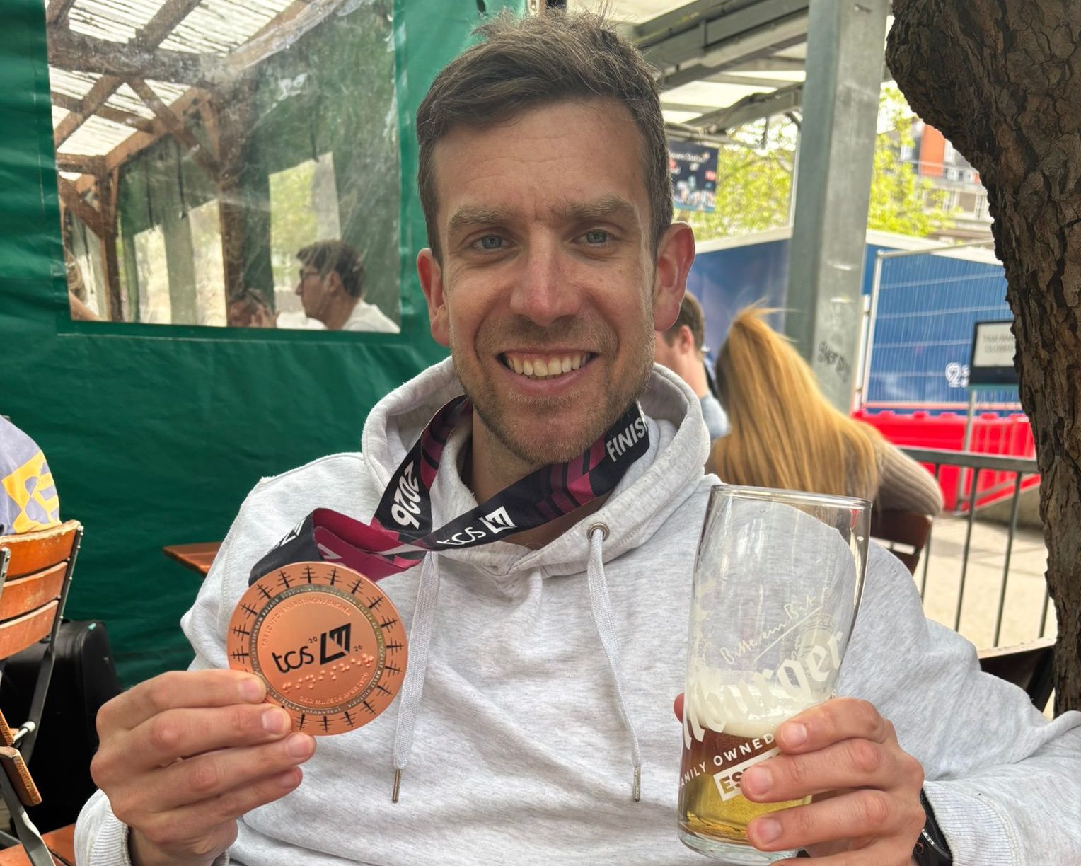 Man holding a London Marathon medal and a pint of beer smiling at the camera