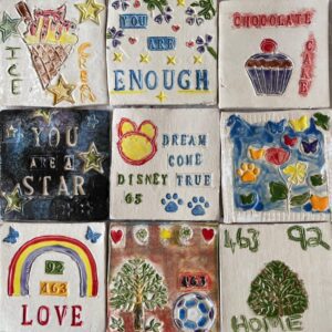 rows of colourful painted ceramic tiles with rainbows and messages of hope