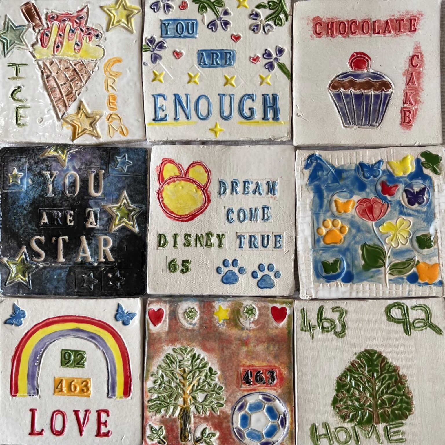 rows of colourful painted ceramic tiles with rainbows and messages of hope