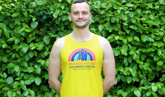 Man wearing a bright yellow running vest with a red, blue and green rainbow logo on the front