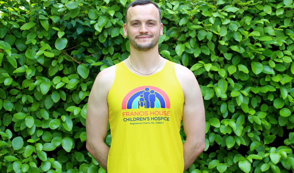 Man wearing a bright yellow running vest with a red, blue and green rainbow logo on the front